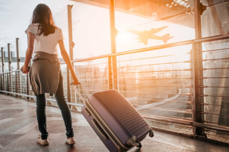 Woman walking though airport at sunset