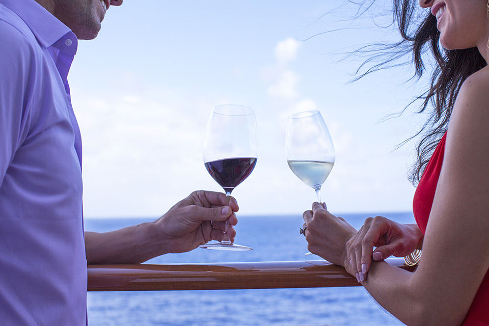 Couple sharing glasses of wine while on the deck on Norwegian Cruise Line (NCL)