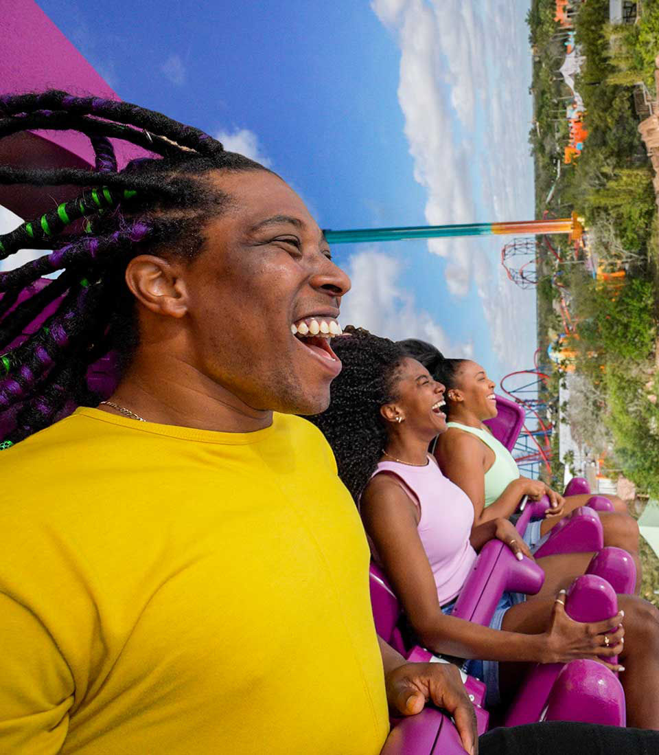 Family riding a bright purple roller coaster ride at busch gardens smiling and laughing.