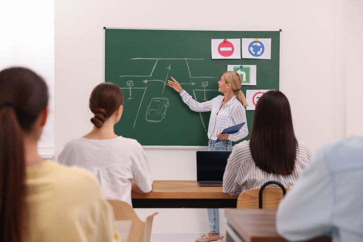 Teacher explaining traffic rules to audience during lesson in driving school