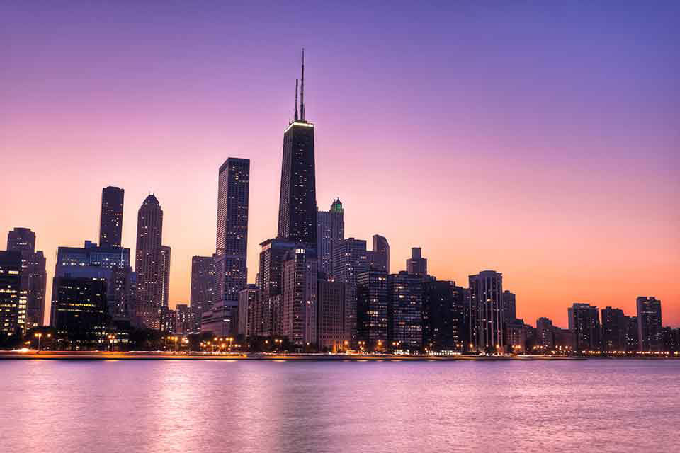 Chicago skyscrapers with water below at during sunset.