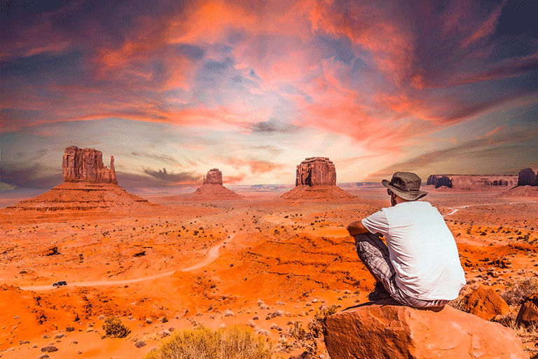 Man sitting on a boulder and looking at the landscape on a Trafalgar Tour in Monument Valley National Park.