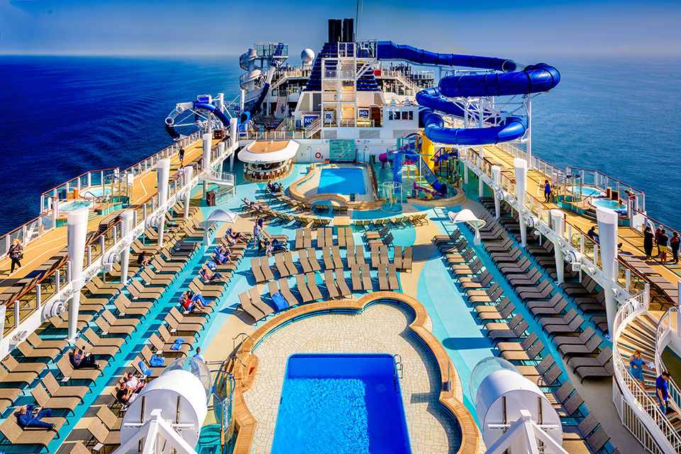 View of the Norwegian Bliss pool deck, lounge chairs and slide while at sea.