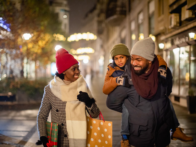 Young couple with their child in winter clothing shopping for the holidays.