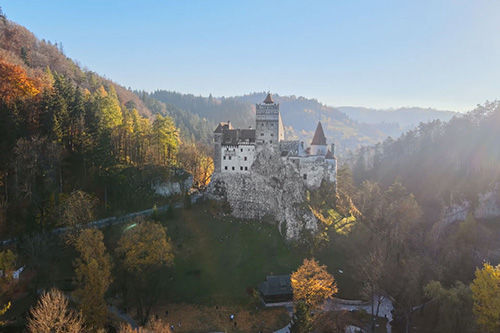 An old castle on a hilltop in Transylvania with mountains in the background.