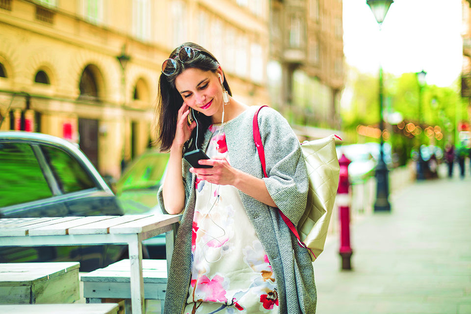 Young adult woman listening to a podcast and smiling.