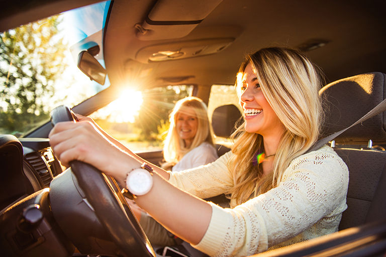 A woman driving her car with her mother next to her.