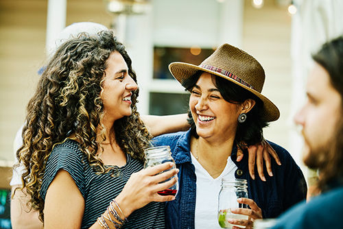 Medium shot of smiling female friends embracing while dining at food truck