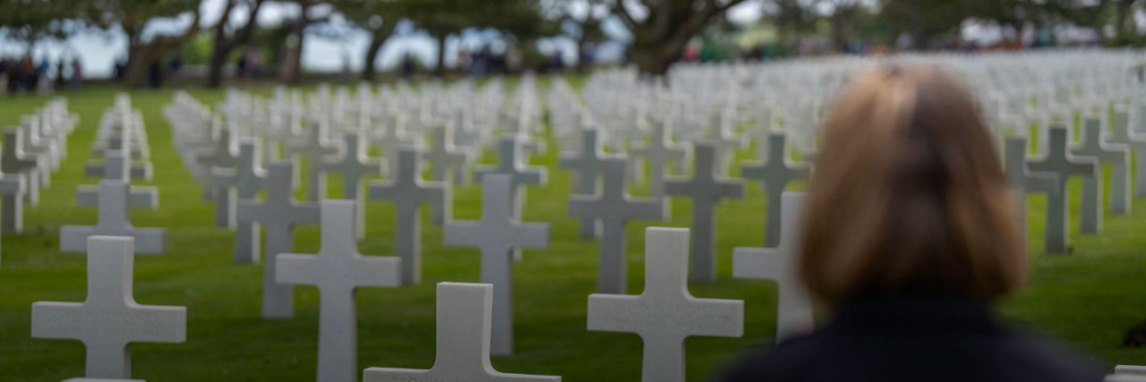Woman standing in a cemetery in front of white cross headstones
