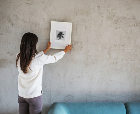 Woman hanging picture on wall.