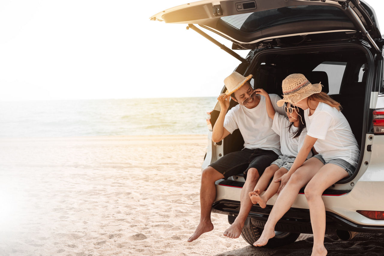 Family sitting in car on the beach
