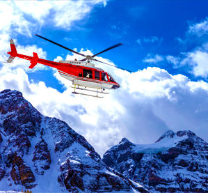 helicopter flying over snowcapped mountains