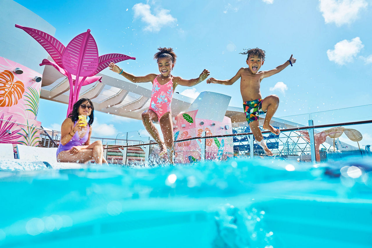 WN, Wonder of the Seas, two kids jumping into water, fun, action, laughing, excitement, woman sitting by pool, relaxing with drink,