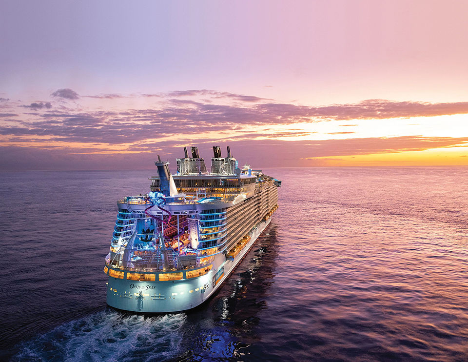 OA, Oasis of the Seas, aerial shot of ship at sea, sunset, dusk, evening, 3/4 aft starboard view, ocean horizon, red, orange, purple colors, AquaTheater and slides at rear of ship, scenic, seascape