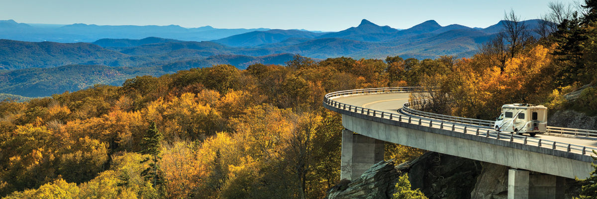 RV on elevated highway overlooking fall leaves and mountains.