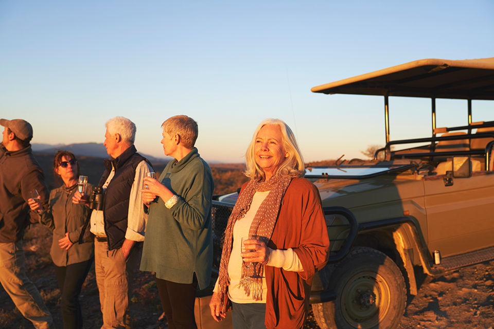 Multi-generational family enjoying a safari experience at sunset with wildlife viewing and scenic landscapes.