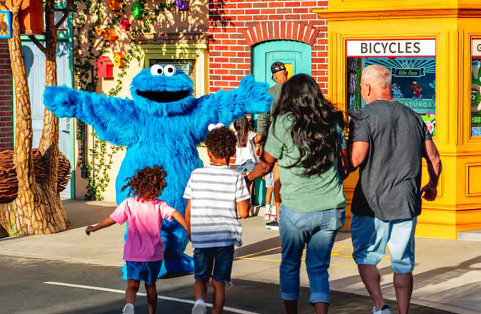 Family running to hug the cookie monster from seasme street.