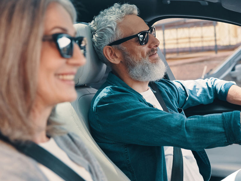 Happy senior couple enjoying car ride while sitting on front seats of the car
