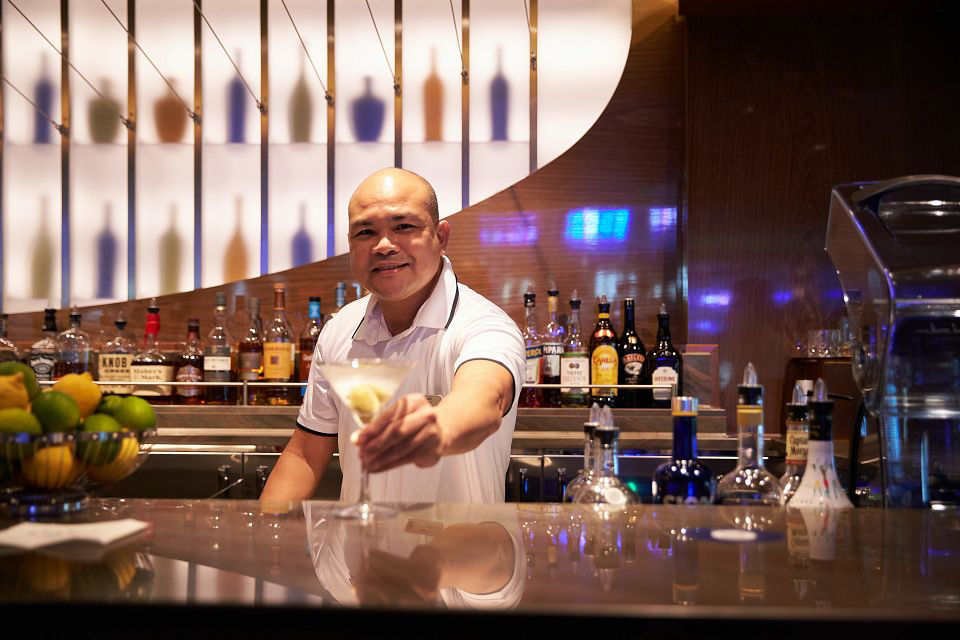 Friendly and smiling service personnel serving guest a drink