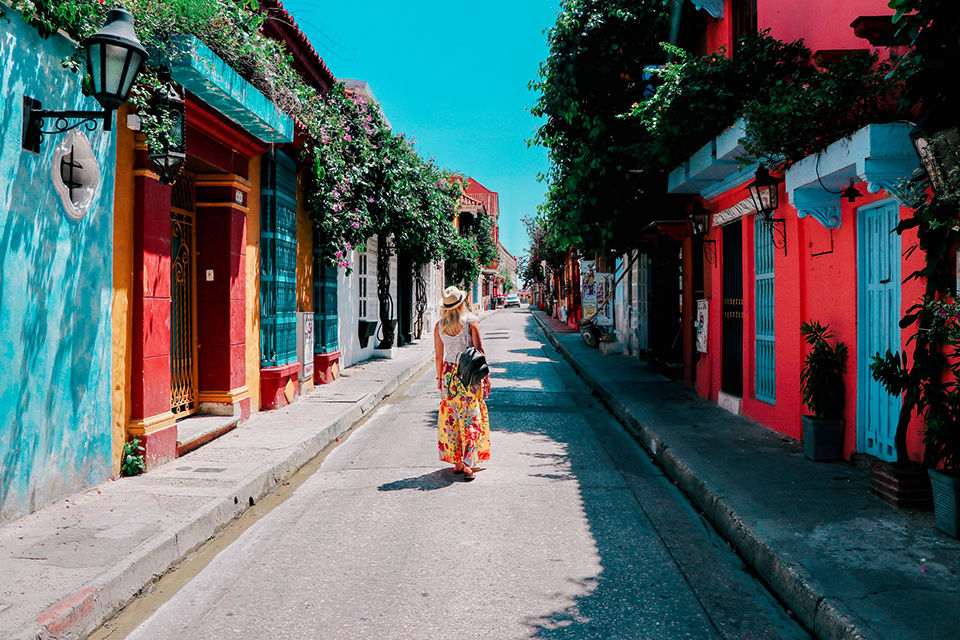 Young woman walking on a colorful street in old city of Cartagena, Colombia.