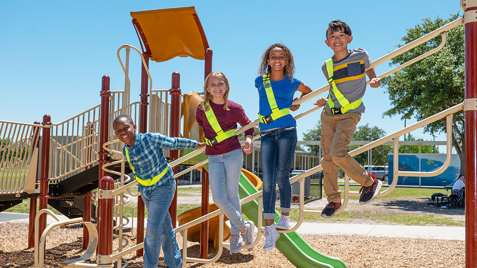 Children in a park wearing their school safety gear.