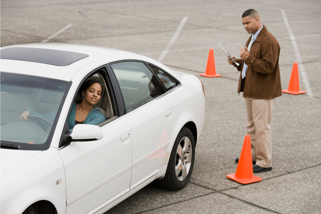 A young teen girl is taking her driving test with an instructor. 