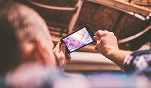 Photo of Caucasian male taking a photo with his mobile phone of pipes above him