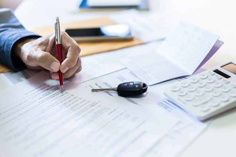 Car keys, calculator, and car insurance coverage statements