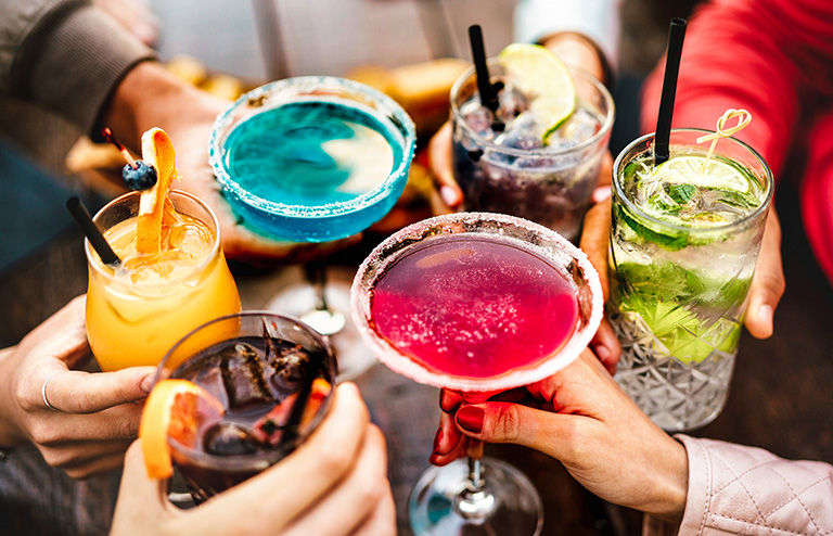 shot of friends toasting multicolored fancy drinks.