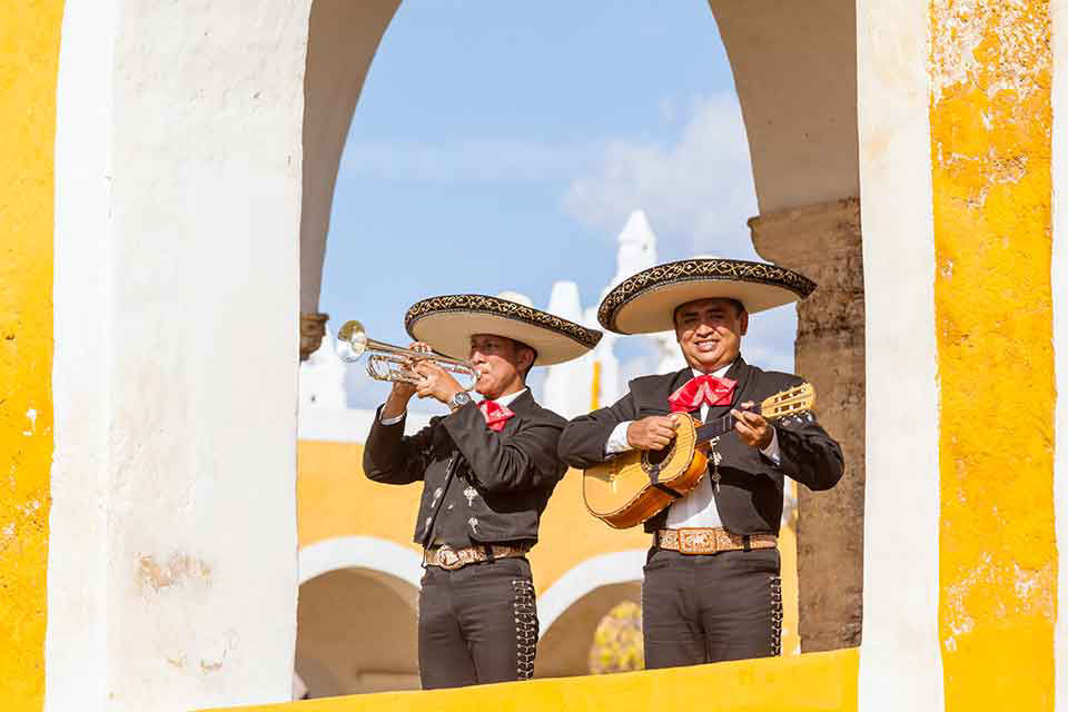 two gentlemen in a mariachi band are playing the trumpet and guitar 