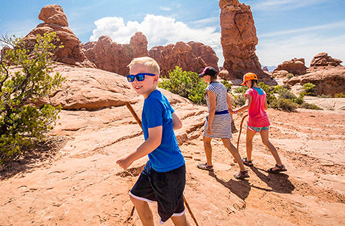 A family of three exploring the red rocks in a national park in the US