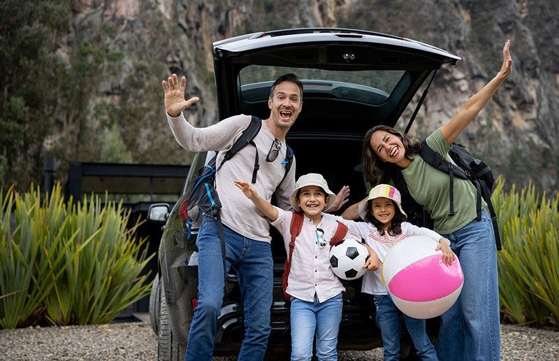 Happy Latin American family enjoying their vacations and going on a road trip in their car