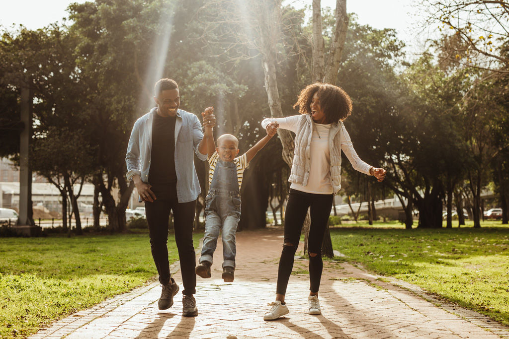 A family walking down a path with mom and dad holding the young kids hand.