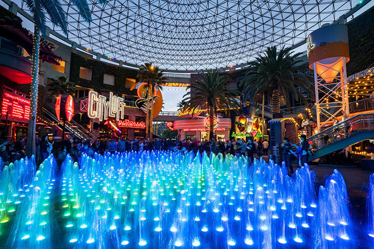 Universal studios citywalk at night with glowing blue water that shoots out from the ground.
