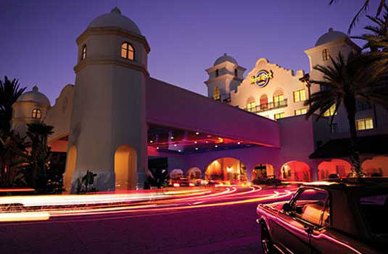 Nightime view of the front of universal's hard rock hotel as cars drive into the valet area.