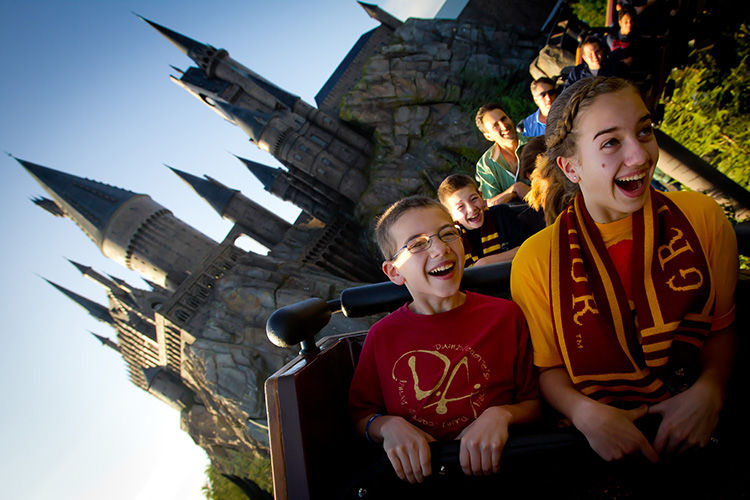 Brother and sister sit in the front of a roller coaster ride in universal's harry potter world.