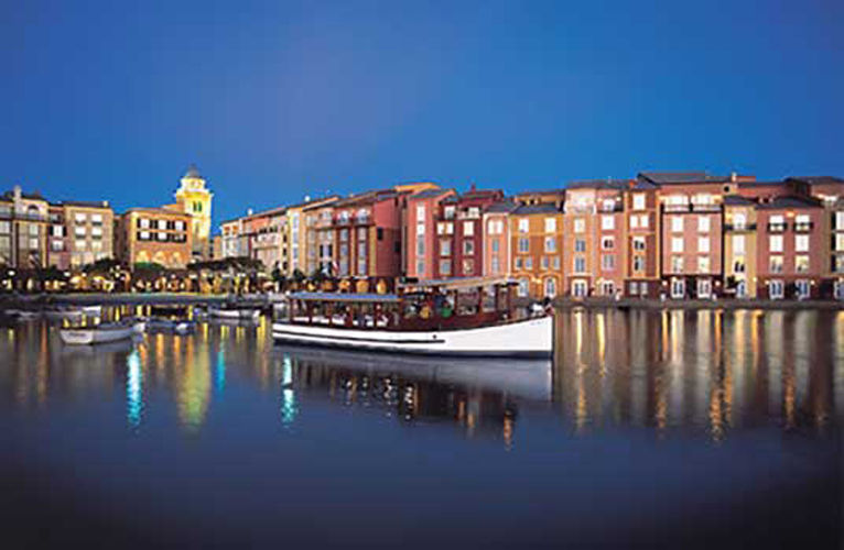 Nighttime view of universal's loews portofino bay hotel dockside with boats in the water.