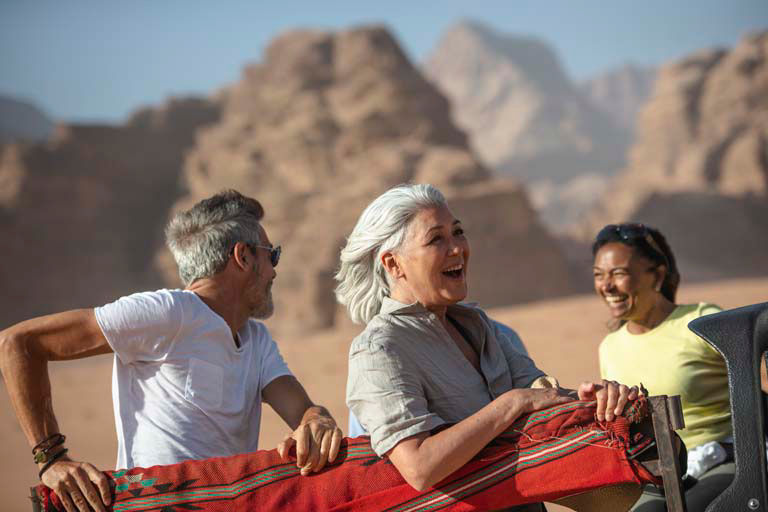 Travelers enjoying shared moment against dramatic red rock desert landscape backdrop