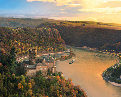 Viking cruise ship cruising on river, passing by a castle in Europe