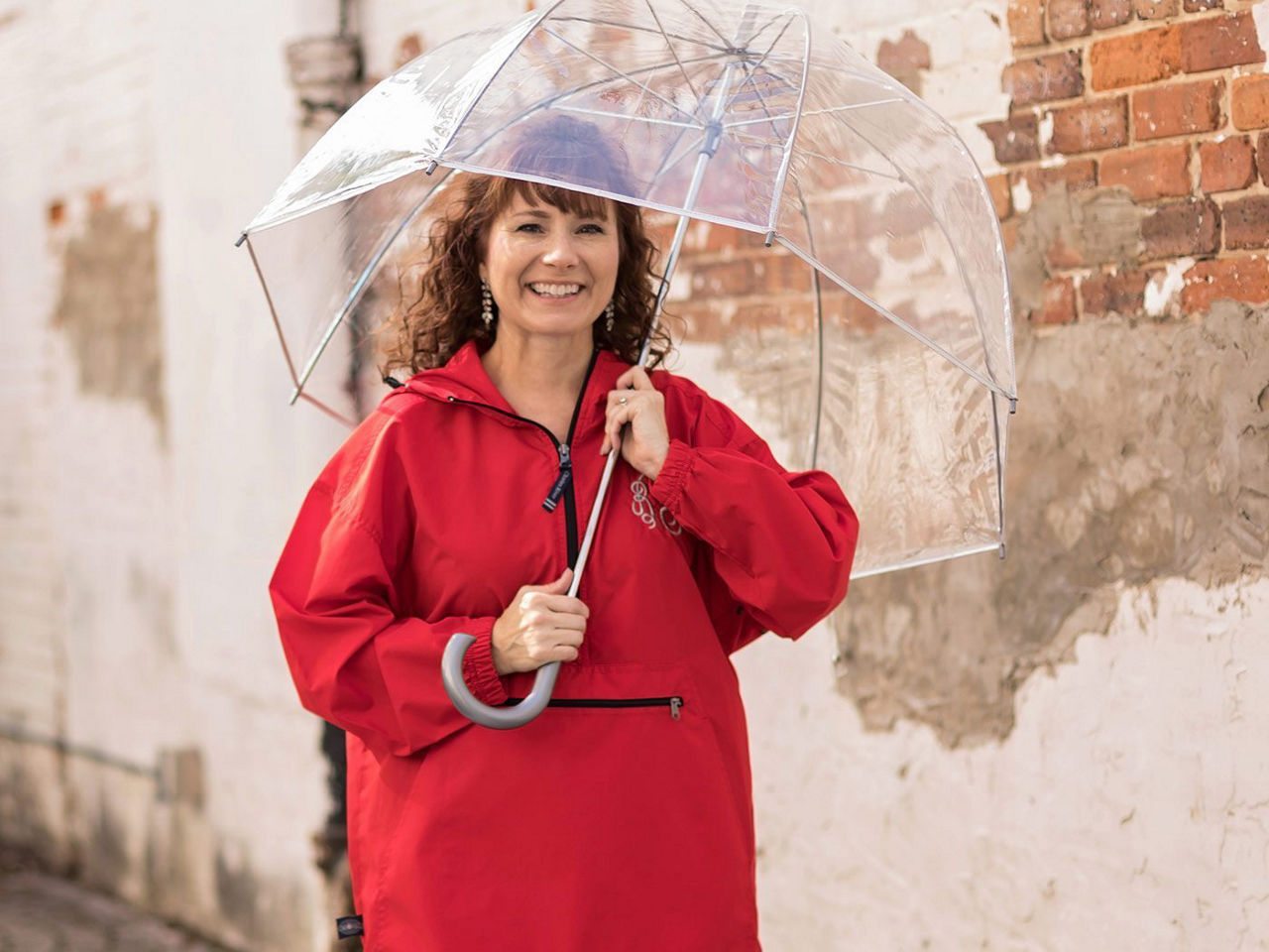 A women wearing a bright red raincoat and holding an umbrella.