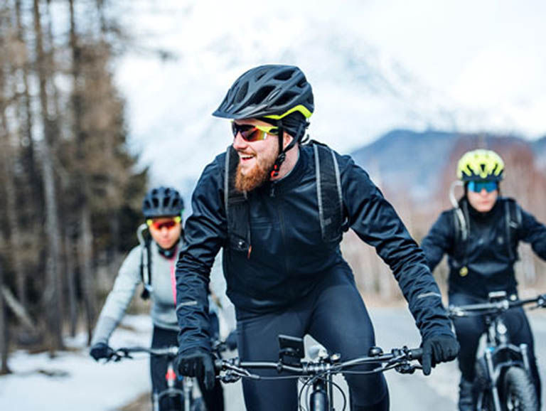 Three friends road biking in the winter on a paved road.