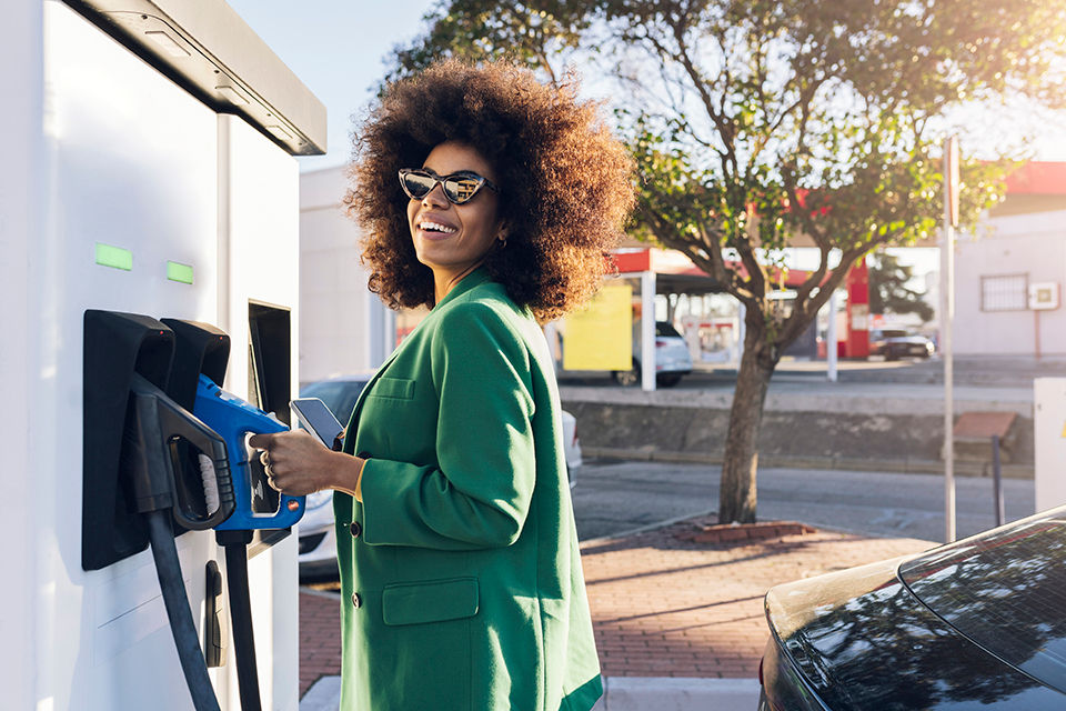 Happy businesswoman with fuel pump at gas station