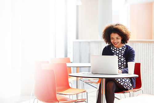 Women sits at a table shopping on her laptop. 