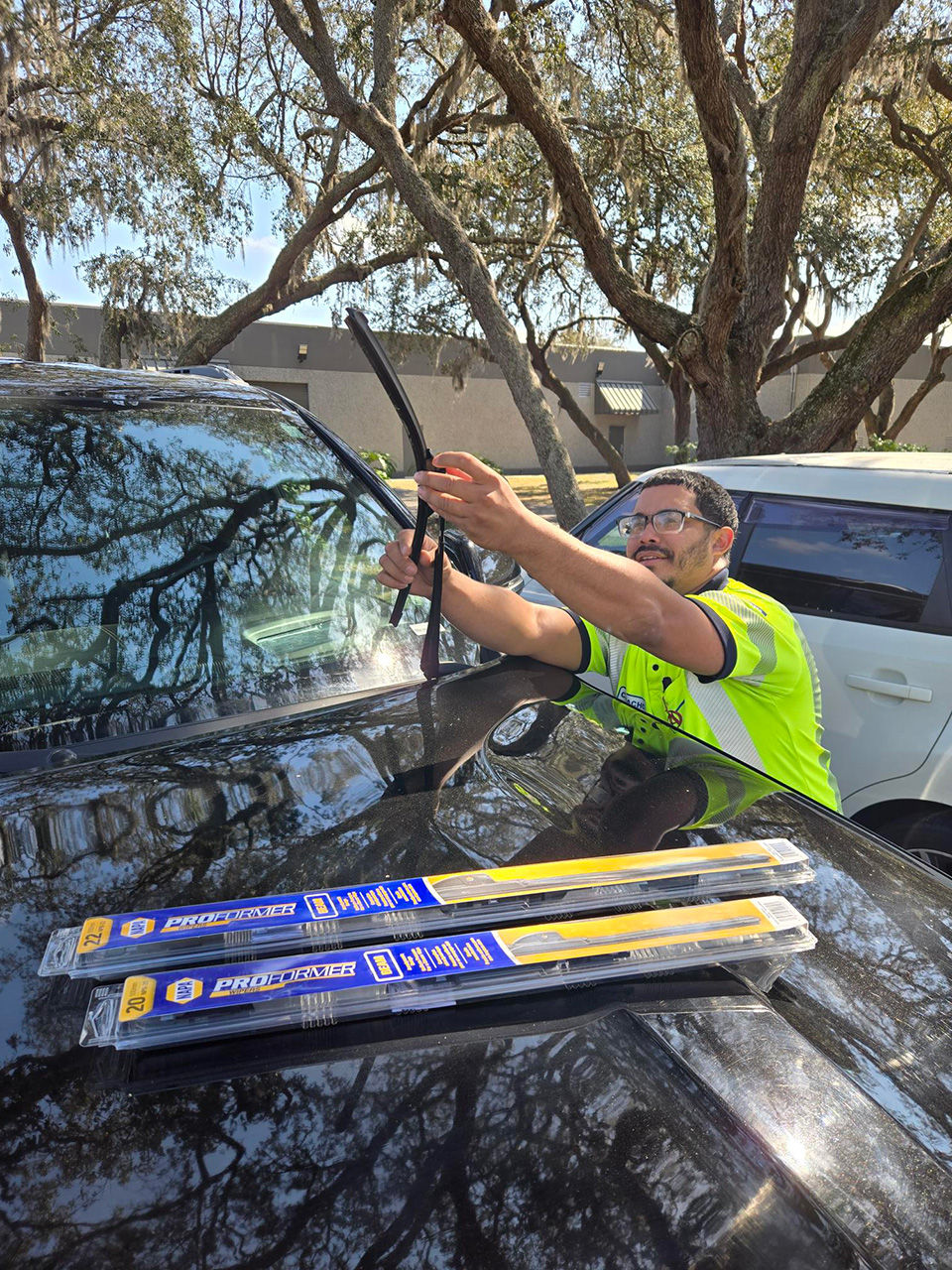 AAA roadside assistance technician replacing the windshield wiper on a car.