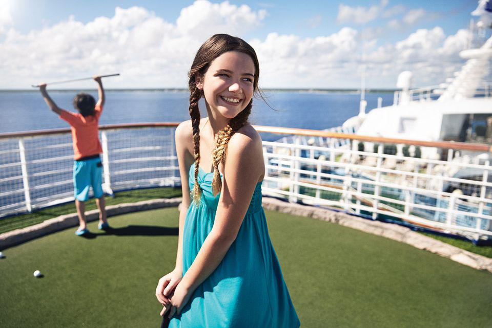 Brother and sister playing mini golf in the open-air deck on Princess cruise.