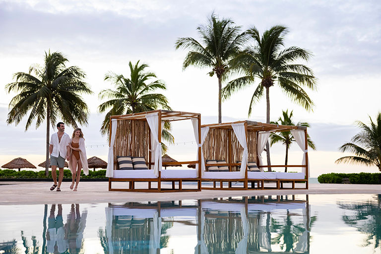 resort pool and cabanas with palm trees in the background.
