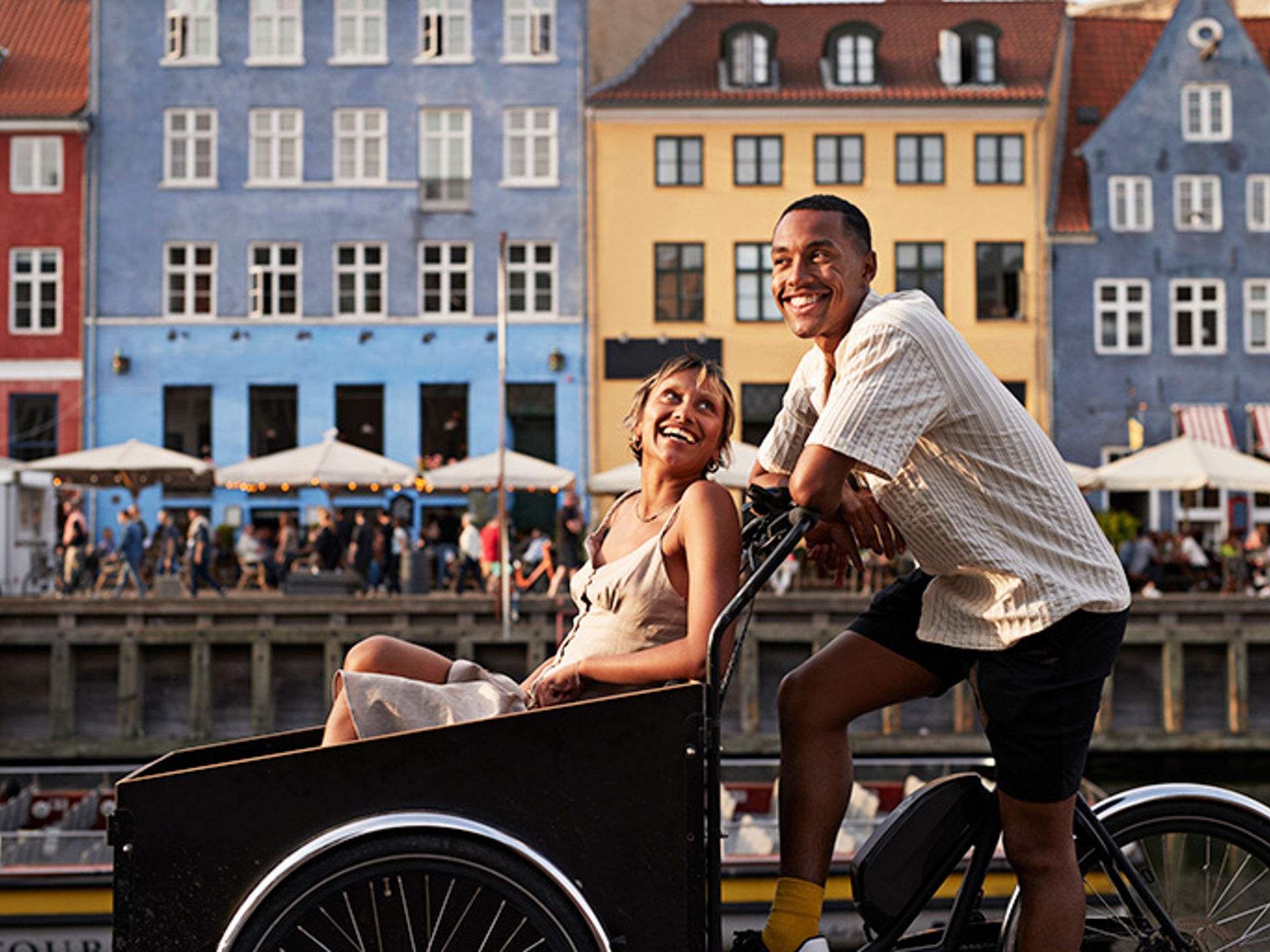 Happy young man with girlfriend in cargo bike at famous pier in Europe.