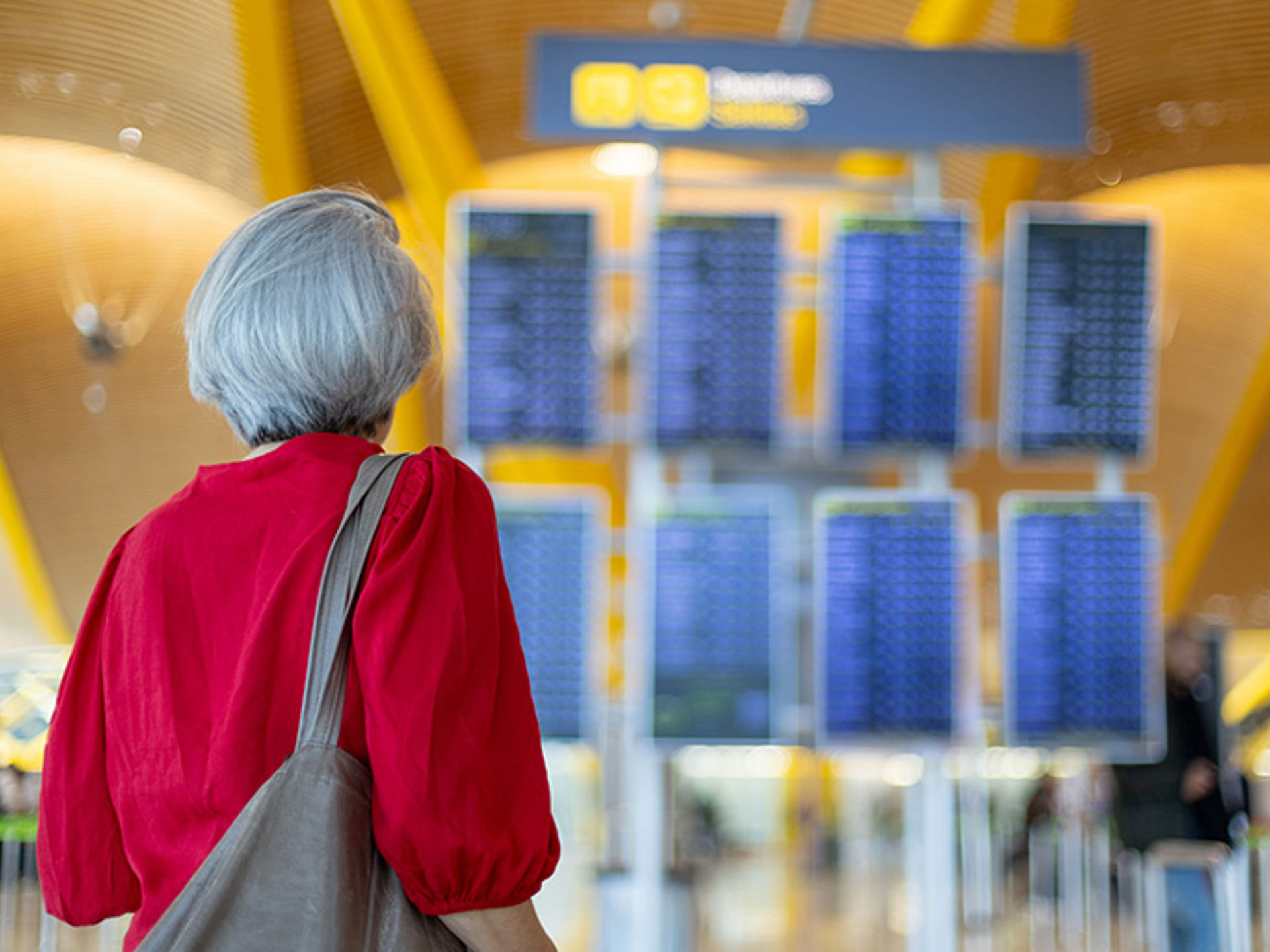Senior woman looking at timetable board while waiting her flight departure at the airport.