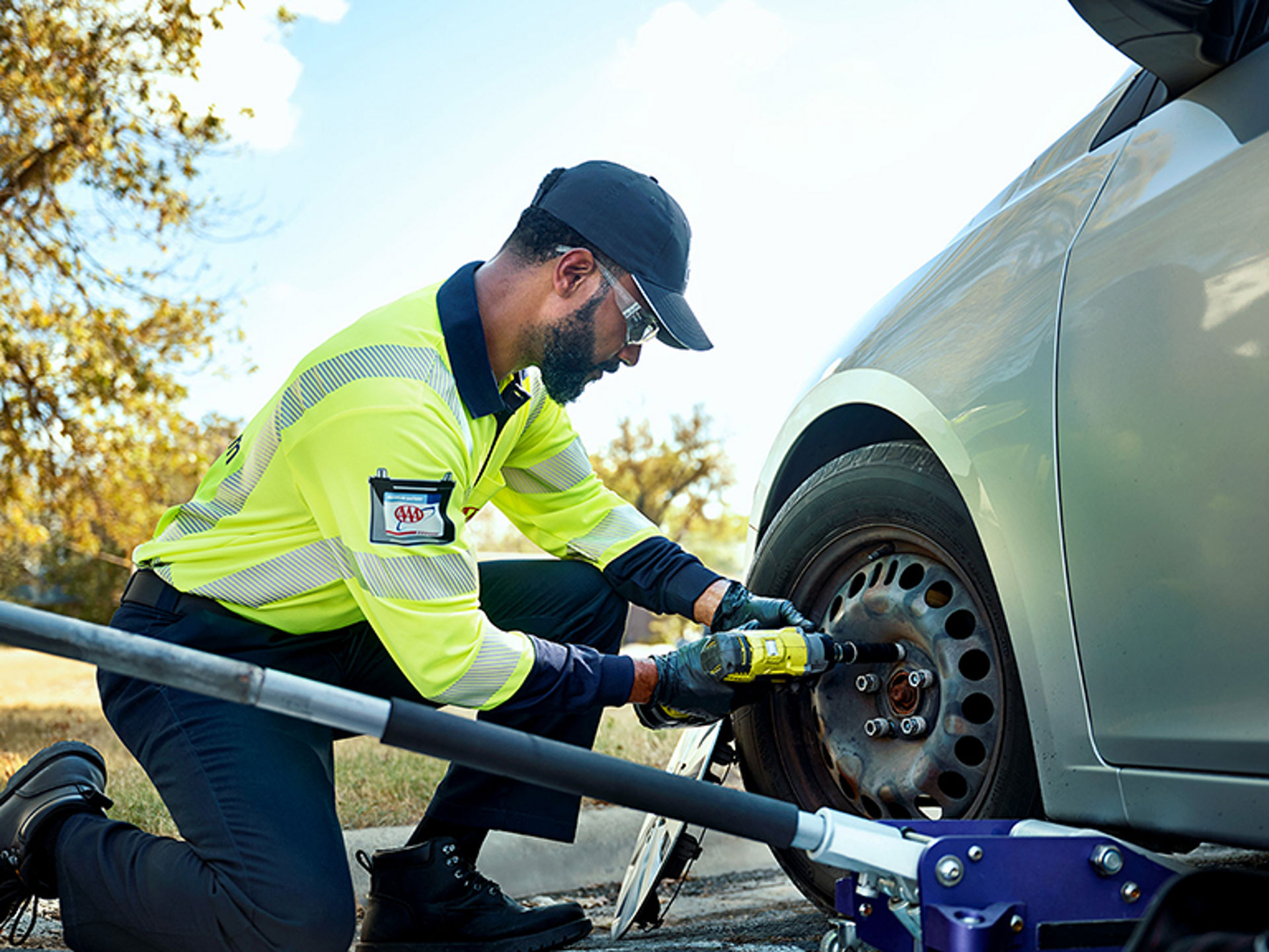 AAA roadside assistance technician replacing a flat tire.